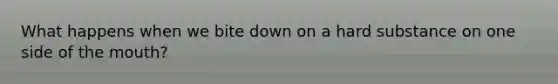 What happens when we bite down on a hard substance on one side of the mouth?