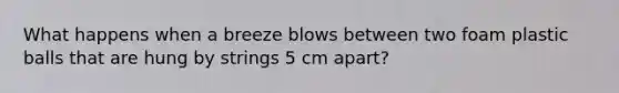 What happens when a breeze blows between two foam plastic balls that are hung by strings 5 cm apart?