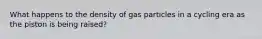 What happens to the density of gas particles in a cycling era as the piston is being raised?