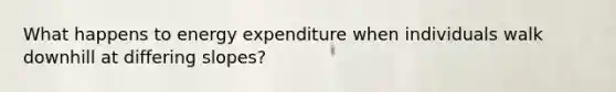 What happens to energy expenditure when individuals walk downhill at differing slopes?