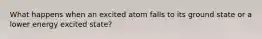 What happens when an excited atom falls to its ground state or a lower energy excited state?