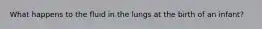 What happens to the fluid in the lungs at the birth of an infant?