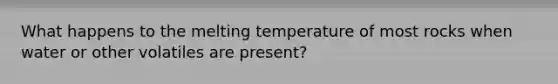 What happens to the melting temperature of most rocks when water or other volatiles are present?