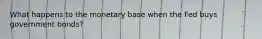What happens to the monetary base when the Fed buys government bonds?
