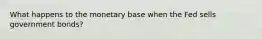 What happens to the monetary base when the Fed sells government bonds?