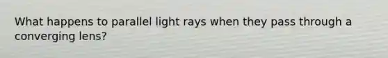 What happens to parallel light rays when they pass through a converging lens?