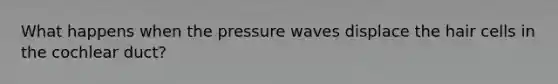 What happens when the pressure waves displace the hair cells in the cochlear duct?