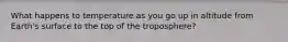 What happens to temperature as you go up in altitude from Earth's surface to the top of the troposphere?