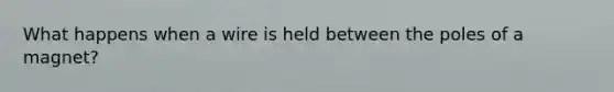 What happens when a wire is held between the poles of a magnet?