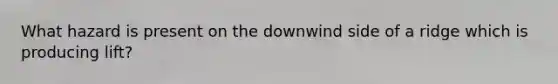 What hazard is present on the downwind side of a ridge which is producing lift?