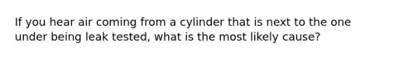 If you hear air coming from a cylinder that is next to the one under being leak tested, what is the most likely cause?