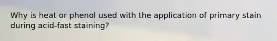 Why is heat or phenol used with the application of primary stain during acid-fast staining?