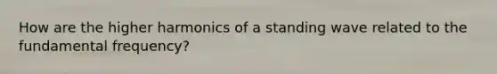 How are the higher harmonics of a standing wave related to the fundamental frequency?