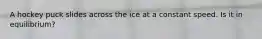 A hockey puck slides across the ice at a constant speed. Is it in equilibrium?