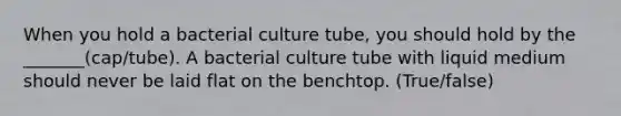 When you hold a bacterial culture tube, you should hold by the _______(cap/tube). A bacterial culture tube with liquid medium should never be laid flat on the benchtop. (True/false)