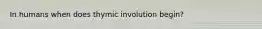 In humans when does thymic involution begin?