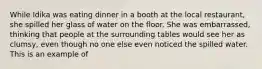 While Idika was eating dinner in a booth at the local restaurant, she spilled her glass of water on the floor. She was embarrassed, thinking that people at the surrounding tables would see her as clumsy, even though no one else even noticed the spilled water. This is an example of