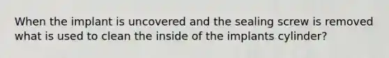 When the implant is uncovered and the sealing screw is removed what is used to clean the inside of the implants cylinder?