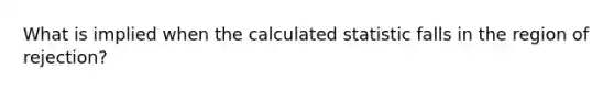 What is implied when the calculated statistic falls in the region of rejection?