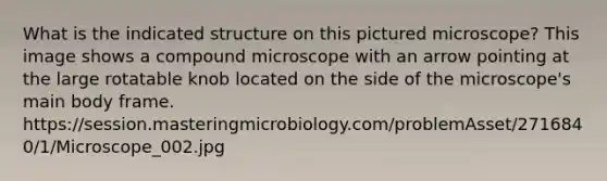 What is the indicated structure on this pictured microscope? This image shows a compound microscope with an arrow pointing at the large rotatable knob located on the side of the microscope's main body frame. https://session.masteringmicrobiology.com/problemAsset/2716840/1/Microscope_002.jpg