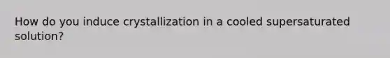 How do you induce crystallization in a cooled supersaturated solution?