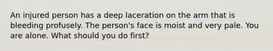 An injured person has a deep laceration on the arm that is bleeding profusely. The person's face is moist and very pale. You are alone. What should you do first?