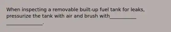 When inspecting a removable built-up fuel tank for leaks, pressurize the tank with air and brush with___________ _______________.