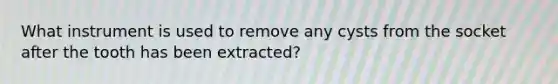 What instrument is used to remove any cysts from the socket after the tooth has been extracted?