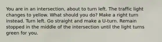 You are in an intersection, about to turn left. The traffic light changes to yellow. What should you do? Make a right turn instead. Turn left. Go straight and make a U-turn. Remain stopped in the middle of the intersection until the light turns green for you.