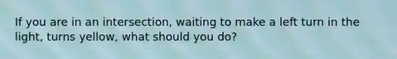 If you are in an intersection, waiting to make a left turn in the light, turns yellow, what should you do?