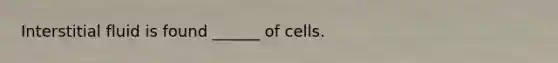 Interstitial fluid is found ______ of cells.