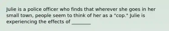 Julie is a police officer who finds that wherever she goes in her small town, people seem to think of her as a "cop." Julie is experiencing the effects of ________