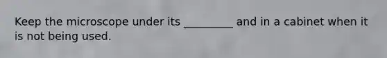 Keep the microscope under its _________ and in a cabinet when it is not being used.