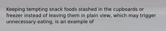 Keeping tempting snack foods stashed in the cupboards or freezer instead of leaving them in plain view, which may trigger unnecessary eating, is an example of