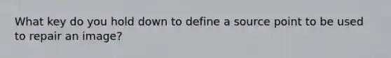 What key do you hold down to define a source point to be used to repair an image?