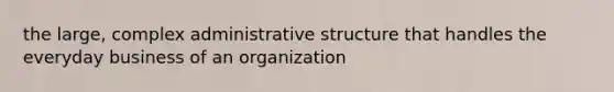 the large, complex administrative structure that handles the everyday business of an organization