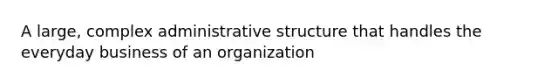 A large, complex administrative structure that handles the everyday business of an organization