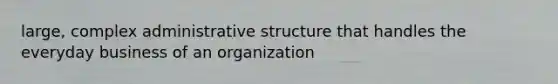 large, complex administrative structure that handles the everyday business of an organization