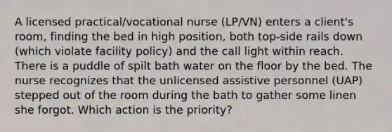 A licensed practical/vocational nurse (LP/VN) enters a client's room, finding the bed in high position, both top-side rails down (which violate facility policy) and the call light within reach. There is a puddle of spilt bath water on the floor by the bed. The nurse recognizes that the unlicensed assistive personnel (UAP) stepped out of the room during the bath to gather some linen she forgot. Which action is the priority?