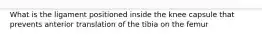 What is the ligament positioned inside the knee capsule that prevents anterior translation of the tibia on the femur