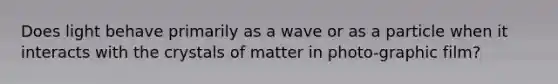 Does light behave primarily as a wave or as a particle when it interacts with the crystals of matter in photo-graphic film?