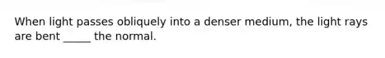 When light passes obliquely into a denser medium, the light rays are bent _____ the normal.