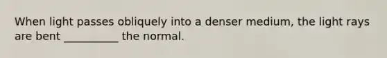 When light passes obliquely into a denser medium, the light rays are bent __________ the normal.