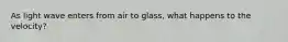 As light wave enters from air to glass, what happens to the velocity?