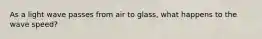 As a light wave passes from air to glass, what happens to the wave speed?