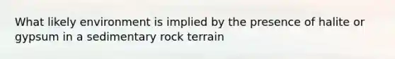 What likely environment is implied by the presence of halite or gypsum in a sedimentary rock terrain