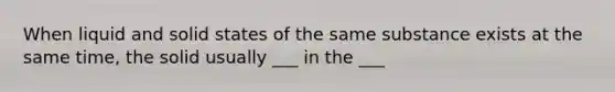 When liquid and solid states of the same substance exists at the same time, the solid usually ___ in the ___