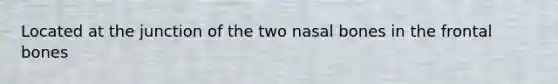 Located at the junction of the two nasal bones in the frontal bones