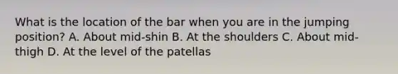 What is the location of the bar when you are in the jumping position? A. About mid-shin B. At the shoulders C. About mid-thigh D. At the level of the patellas