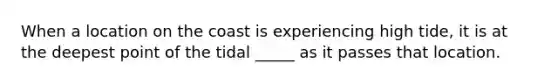 When a location on the coast is experiencing high tide, it is at the deepest point of the tidal _____ as it passes that location.